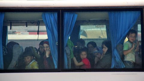 Women and children look out from a bus window.