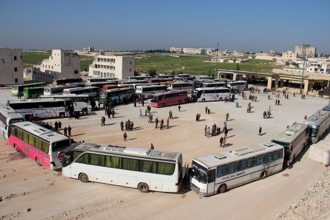 Syrians board a convoy of buses.