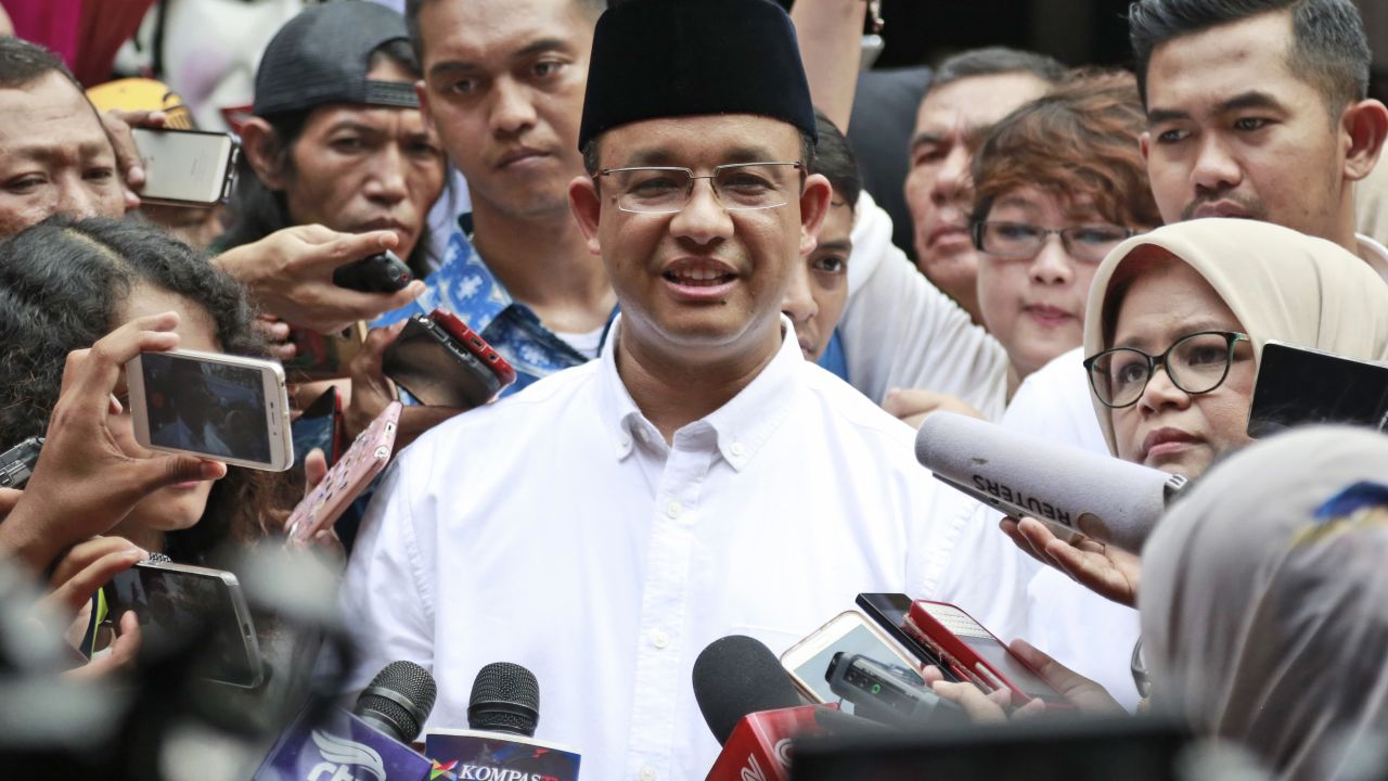 Likely gubernatorial winner Anies Baswedan, center, faces reporters Wednesday after voting in Jakarta.