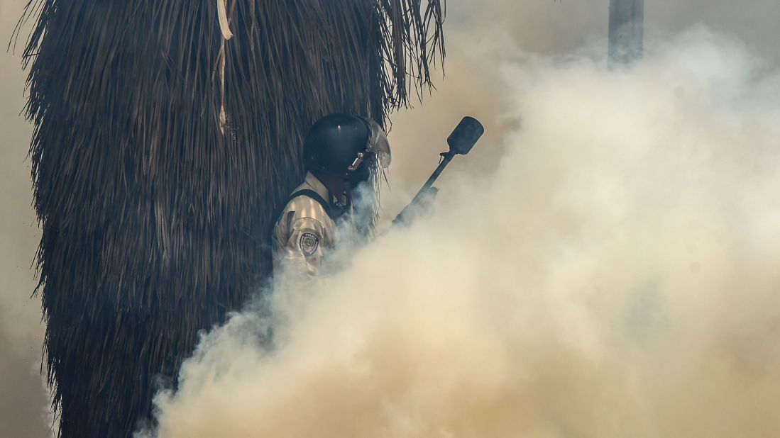 Riot police clash with demonstrators while tear gas fills the air in Caracas on April 19.