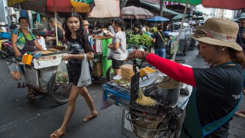 A vendor prepares a waffle on her street food cart at a local market in downtown Bangkok.