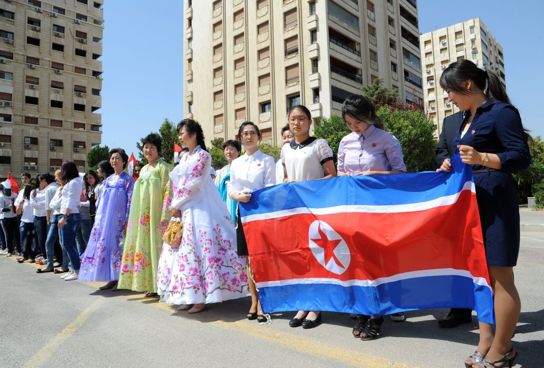 Young women hold a North Korean flag during a ceremony to name a park in Damascus after Kim Il-sung, August 31, 2015.