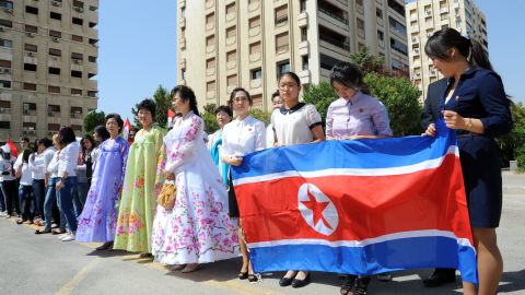 Young women hold a North Korean flag during a ceremony to name a park in Damascus after Kim Il-sung, August 31, 2015.