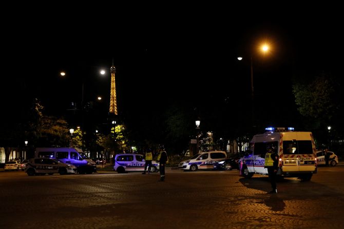 The Eiffel Tower is seen in the background as police officers block the entrance to the Champs-Elysées.