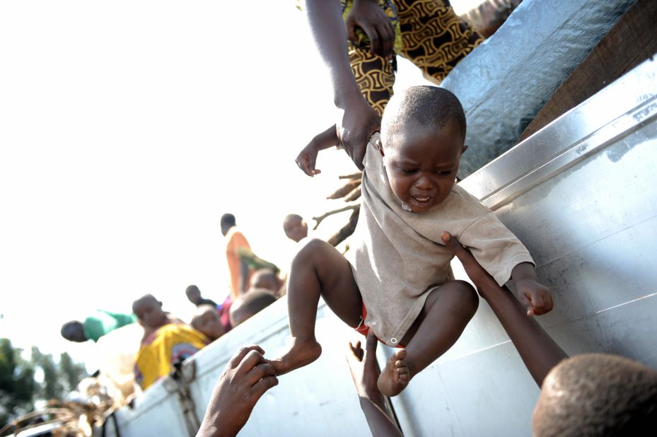 Pictured here, the son of a Congolese park ranger, who had been working in the Virunga National Park, is lifted onto a truck, in November, 2008, as families leave a camp for Internally Displaced People (IDP) in the North Kivu provincial capital of Goma. <br />Park rangers and their families were relocated to a larger IDP camp during violent clashes amongst different militias. Its rangers are not immune to the conflict that has mired the country, and continue to pay the ultimate price for conservation. 
