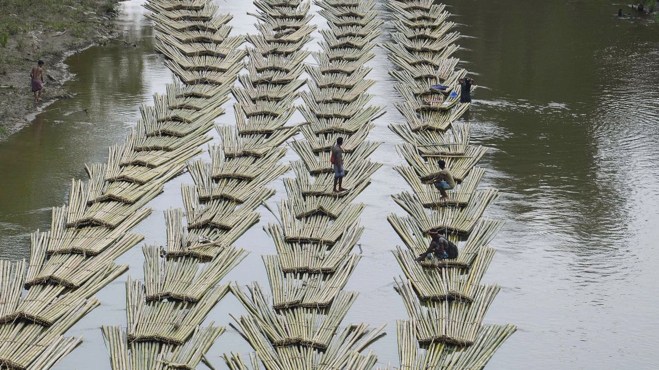 Indian laborers transport bamboo logs down the Longai River in Damchara, India, on Tuesday, April 18.