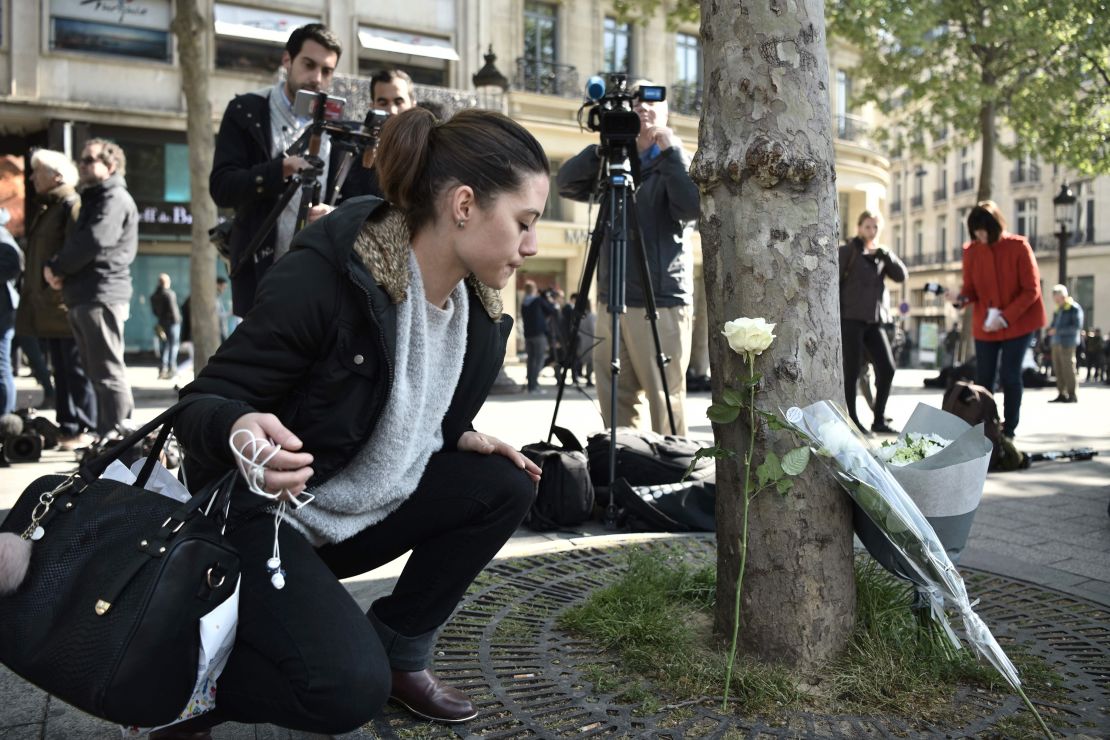 A woman places a flower Friday at the spot where the shooting occurred.