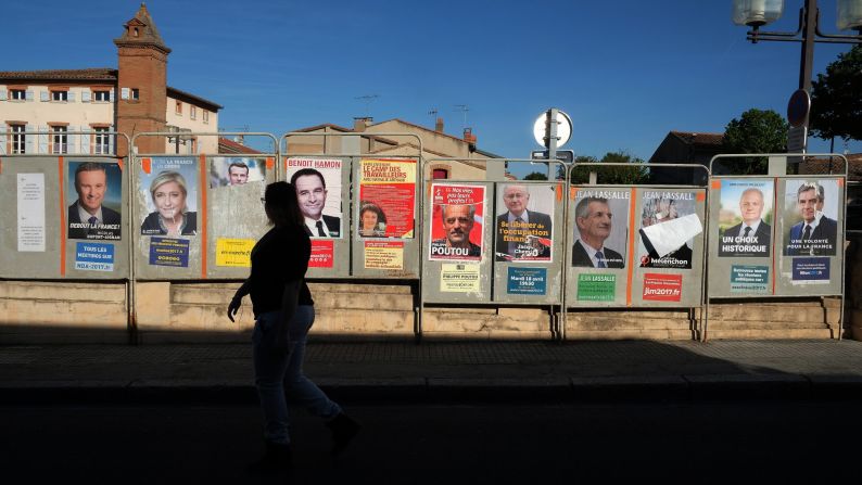 A woman walks past a wall of campaign posters in Villefranche-de-Lauragais. 
