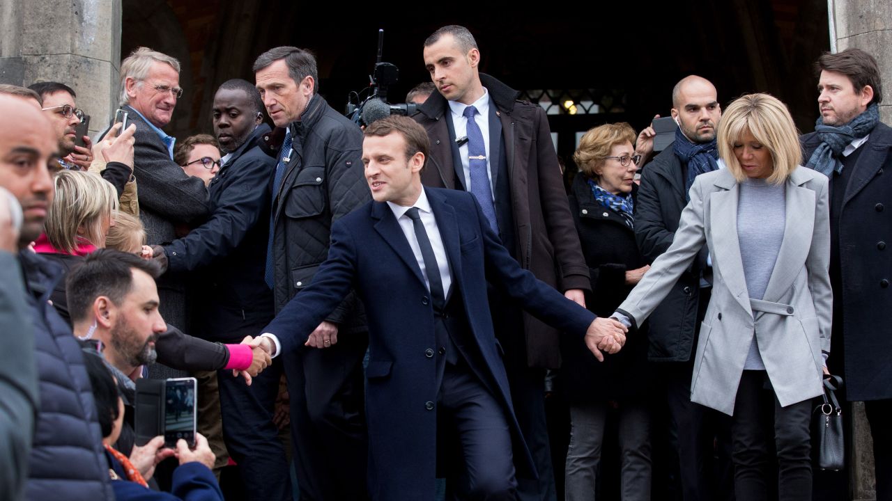 Macron and his wife, Brigitte Trogneux, greet supporters as they leave a polling station in Le Touque.
