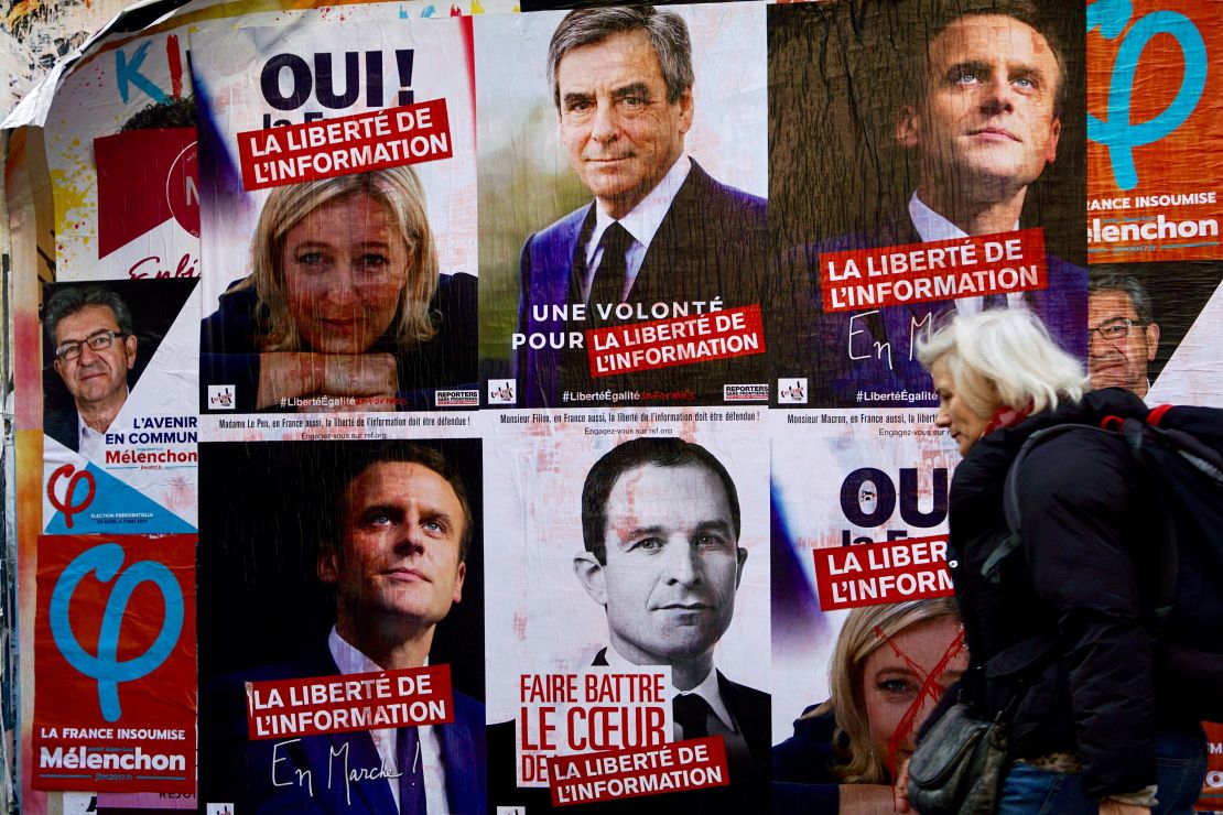 A woman walks past campaign posters for the candidates in the 2017 French presidential election in Paris.