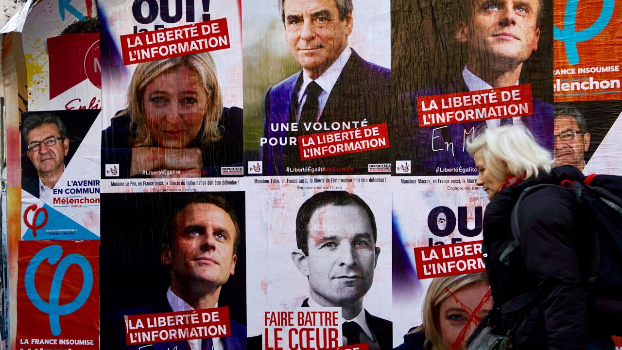 A woman walks past campaign posters for the candidates in the 2017 French presidential election in Paris.