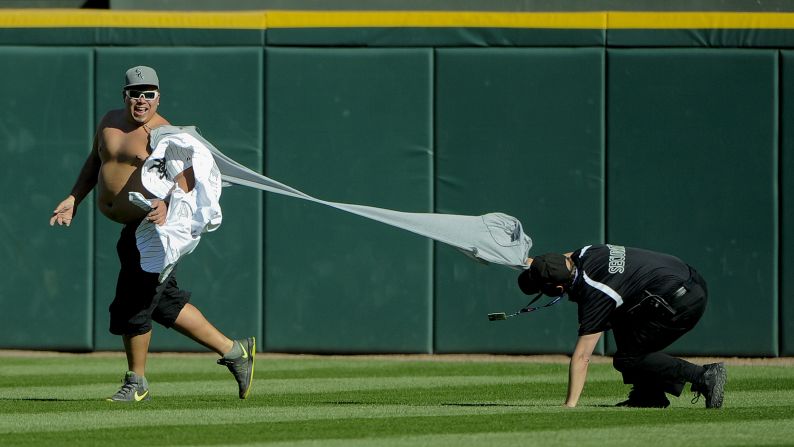 A security guard tries to detain a fan who ran onto the field, interrupting a Major League Baseball game in Chicago on Sunday, April 23.