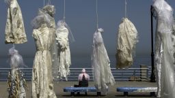 A woman sits on a bench near an installation of wedding dresses by Lebanese artist Mireille Honein and the NGO Abaad at Beirut Corniche on April 22, 2017, in tribute to the victims of the Lebanese penal code article 522. 