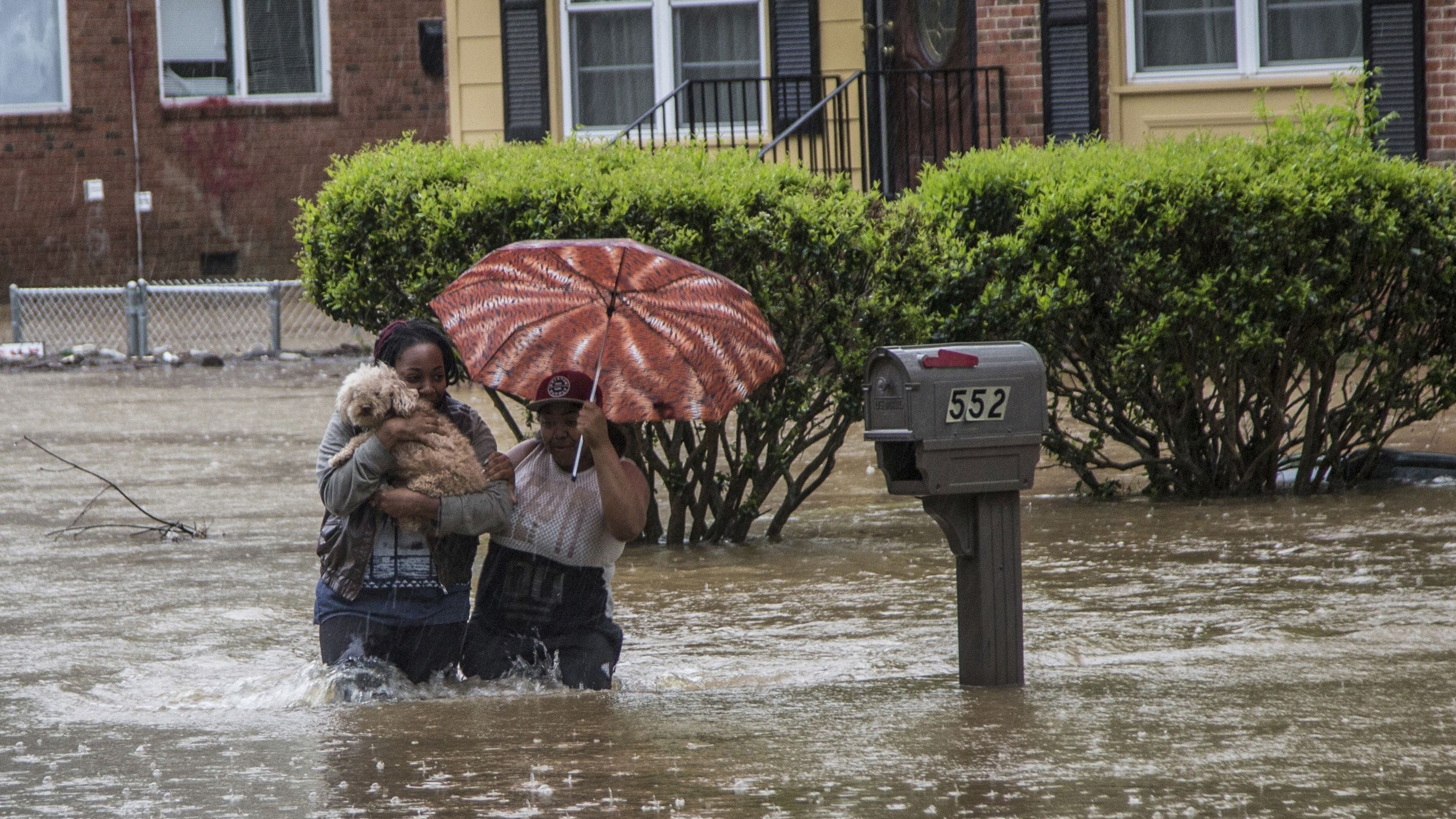 Nautica Jackson, left, and Aniya Ruffin walk through floodwaters with their dog as water threatened to enter their home in Raleigh, North Carolina.