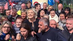 TOPSHOT - French presidential election candidate for the far-right Front National (FN) party, Marine Le Pen (C) smiles with people in front of the Whirlpool factory in Amiens, northern France, on April 26, 2017.French far-right presidential candidate Marine Le Pen upstaged her rival Emmanuel Macron by making a surprise visit to an under-threat factory just as he was visiting the town where it is based. / AFP PHOTO / STR        (Photo credit should read STR/AFP/Getty Images)