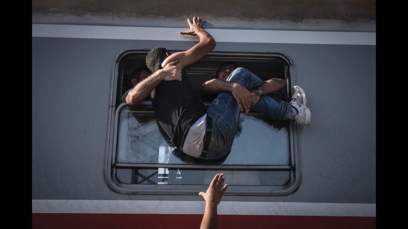 A desperate man is hauled through the window of one of the last trains to carry refugees and migrants from the Croatian border to Zagreb. (September 18, 2015)