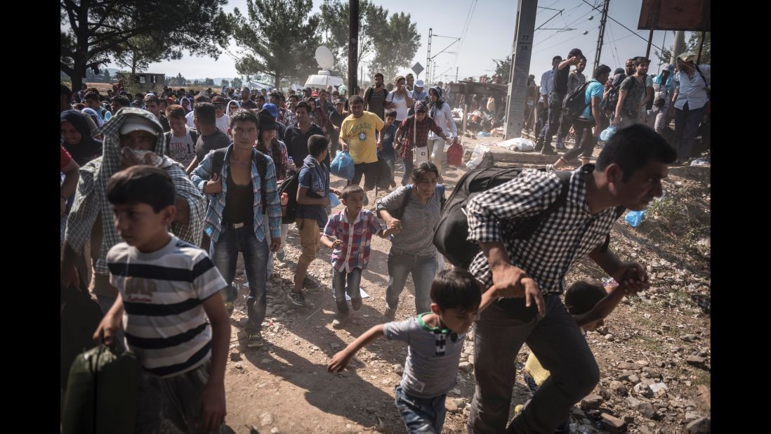 Refugees and migrants rush to board a Macedonian train to take them from the Greek border village of Idomeni towards Serbia. (July 27, 2015)
