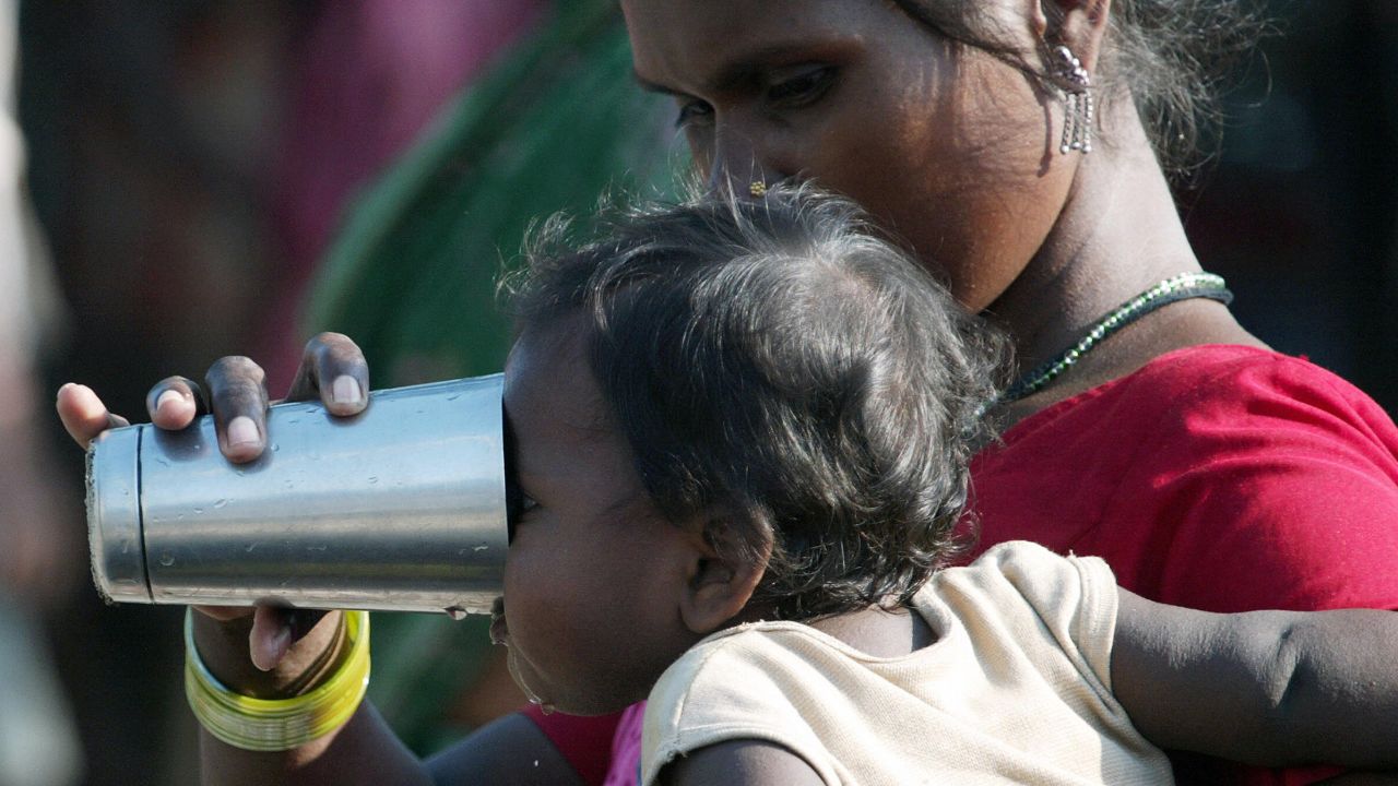 An Indian flood-affected villager gives drinking water to her child at a makeshift camp in the Purnia district of Bihar.