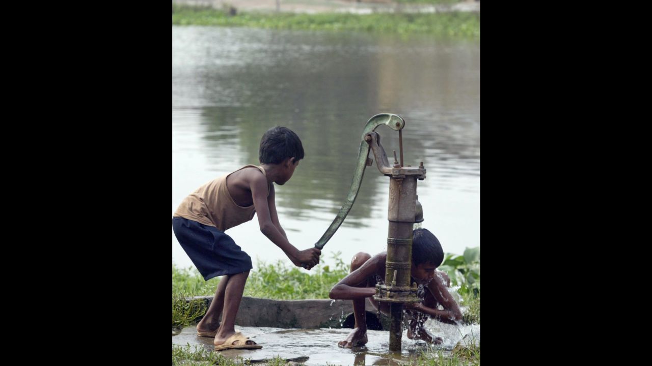 A flood-affected boy pumps water for another to bathe at a village in the northern Indian state of Bihar.