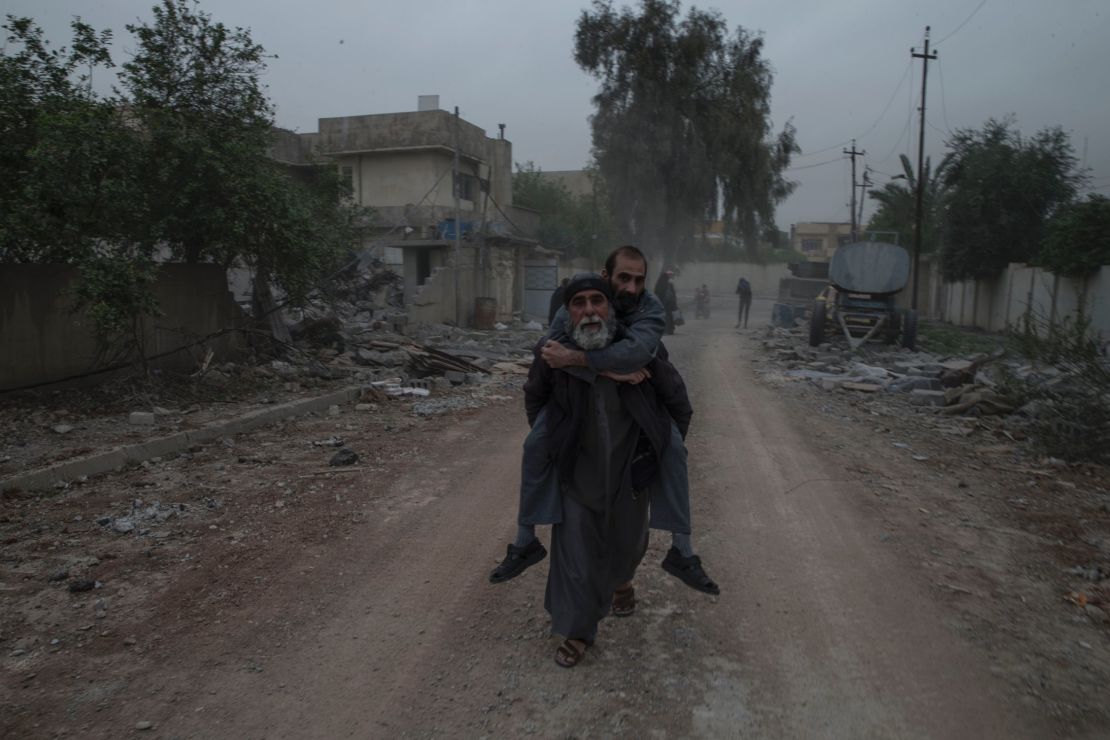 A man carries a sick relative on his back as they flee from their home in west Mosul's al Yarmouk neighborhood on April 11.  