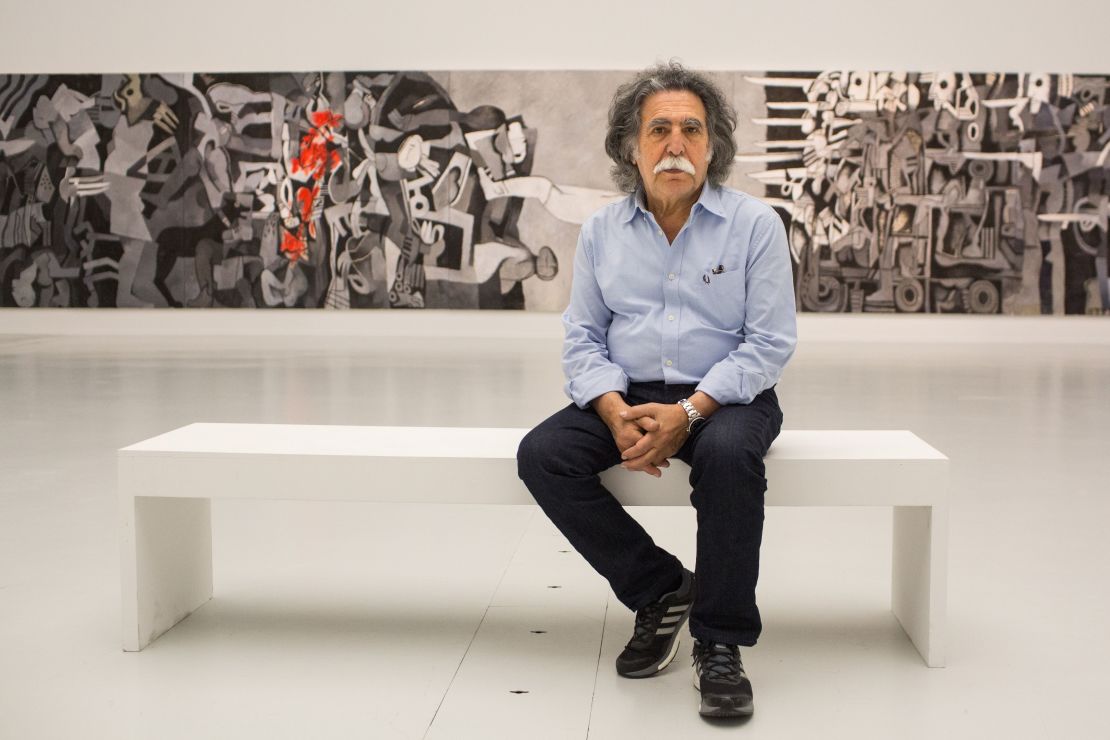 Dia Azzawi pictured in with his work "Mission of Destruction" at the Arab Museum of Modern Art in Doha, Qatar (2016).