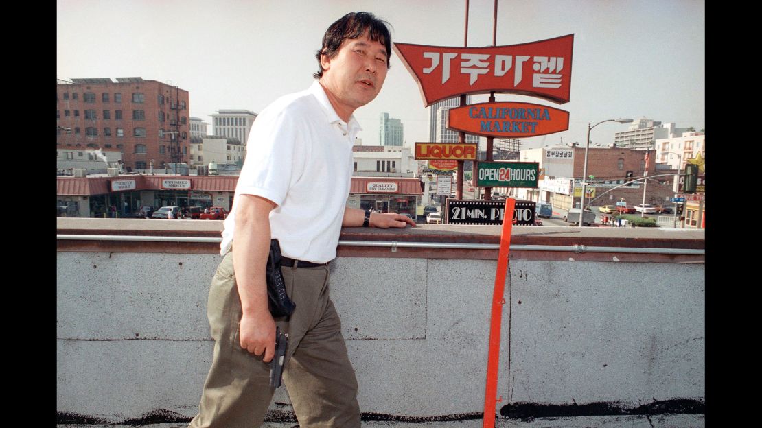 Store owner Richard Rhee stands vigil, armed with a handgun and a cellular phone on the roof of his grocery store in the Koreatown area of Los Angeles on May 2, 1992.