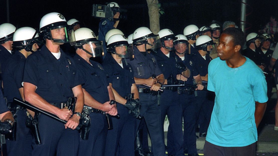 A man passes in front of a line of policemen in Los Angeles, 30 April 1992.