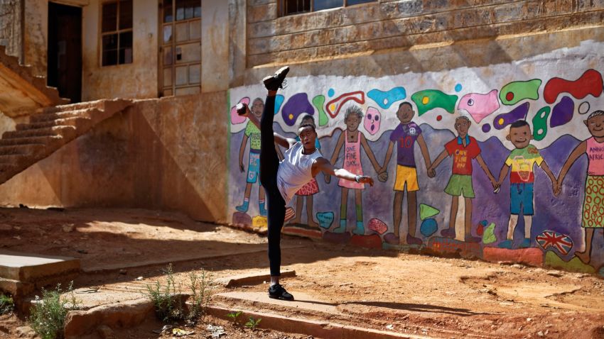 In this photo taken Friday, Dec. 9, 2016, Kenyan ballet dancer Joel Kioko, 16, strikes a pose as a joke as he walks through the courtyard of a school where he was teaching young dancers, in the Kibera slum of Nairobi, Kenya. In a country not usually associated with classical ballet, Kenya's most promising young ballet dancer Joel Kioko has come home for Christmas from his training in the United States, to dance a solo in The Nutcracker and teach holiday classes to aspiring dancers in Kibera, the Kenyan capital's largest slum. (AP Photo/Ben Curtis)