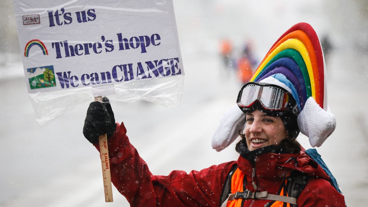 Meteorologist Lis Cohen holds a sign while cheering on protesters in Denver.