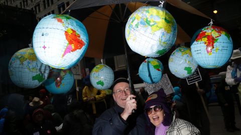 Demonstrators stand under an umbrella with plastic globes during the march in Chicago.