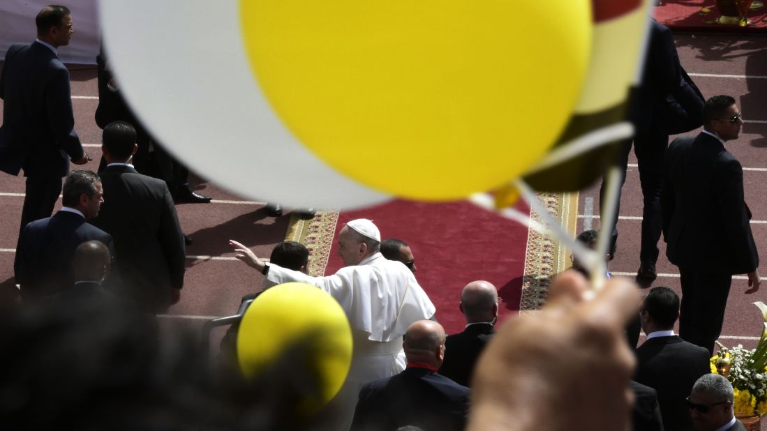 Pope Francis waves at people as he leaves after leading a mass on at a stadium in Cairo. 