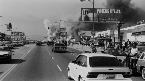 Buildings going up in smoke on an unidentified street during the riots of 1992, following the decision in the Rodney King case. Film still from "LA 92."