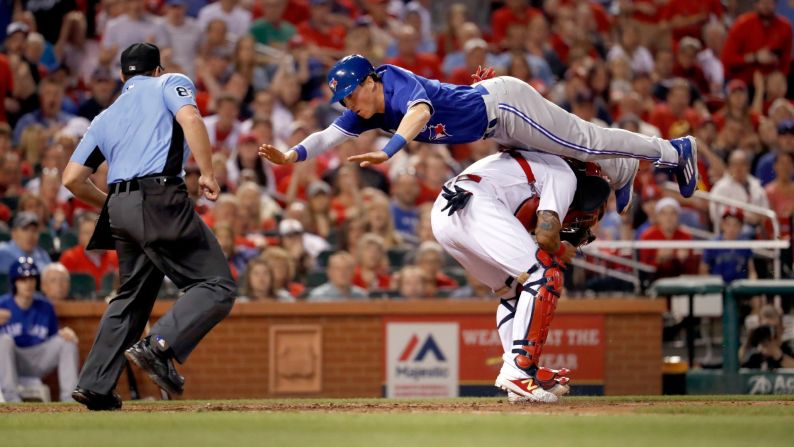 Toronto's Chris Coghlan leaps over St. Louis catcher Yadier Molina to score a run on Tuesday, April 25.