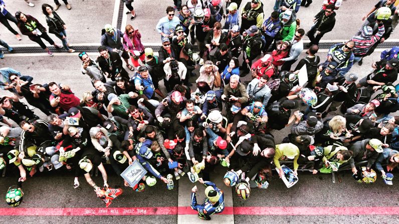 Valentino Rossi signs autographs outside the Yamaha team garage. The 38-year-old is by far the sport's biggest star.