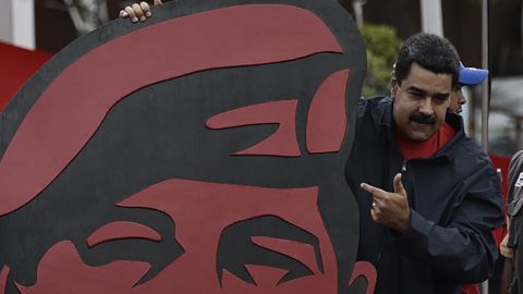 Venezuelan President Nicolás Maduro points to a placard of his mentor, the late Hugo Chavez, in a May Day rally in Caracas.