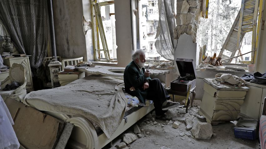 TOPSHOT - Mohammed Mohiedin Anis, or Abu Omar, 70, smokes his pipe as he sits in his destroyed bedroom listening to music on his vinyl player, gramophone, in Aleppo's formerly rebel-held al-Shaar neighbourhood.  / AFP PHOTO / JOSEPH EID        (Photo credit should read JOSEPH EID/AFP/Getty Images)