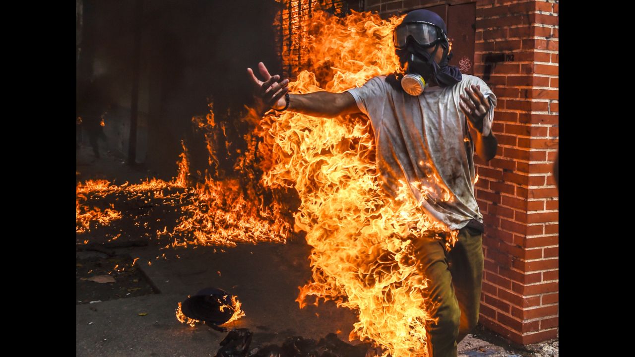 A demonstrator catches fire during protests in Caracas on May 3. It happened as protesters clashed with police and the gas tank of a police motorcycle exploded. Other photos from the scene showed the man being attended for burns to his body.