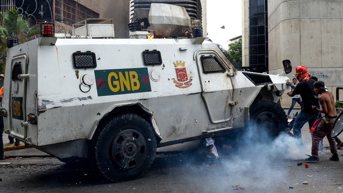 Yaminne, his head covered in a white rag, sits up after being run over by a security vehicle.