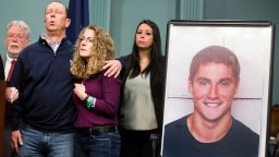 Jim and Evelyn Piazza stand by as Centre County District Attorney Stacy Parks Miller announces the results of an investigation into the death of their son Timothy Piazza, seen in photo at right, a Penn State University fraternity pledge, during a press conference Friday, May 5, 2017, in Bellefonte, Pa. Timothy Piazza had toxic levels of alcohol in his body and was badly injured in a series of falls, authorities said Friday in announcing criminal charges against members of the organization and the frat itself. (Joe Hermitt /PennLive.com via AP)