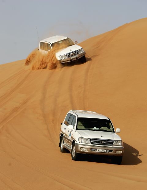 Four Wheel Drives race through the desert as they partake in 'Dunebashing'. Dune bashing is one of the most popular pastimes for tourists when they visit the desert, and involves vehicles driving at high speed over the undulating landscape.