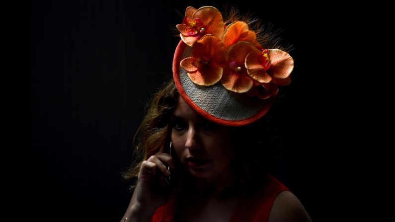 A woman displays orange orchids on her hat.
