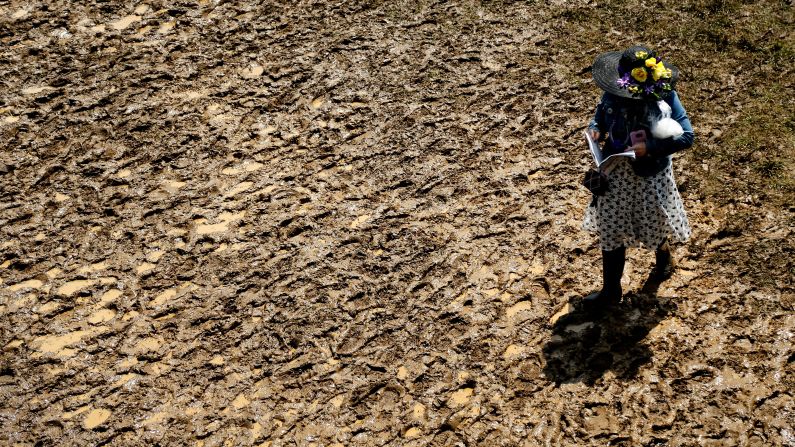 A derby reveler treks through the mud in the infield prior to the race.