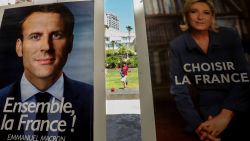 A boy plays with a ball at the French embassy in the Lebanese capital Beirut, behind the election posters of independent centrist French presidential candidate Emmanuel Macron and far-right Front National candidate Marine Le Pen, during the second round of the French presidential vote on May 7, 2017.