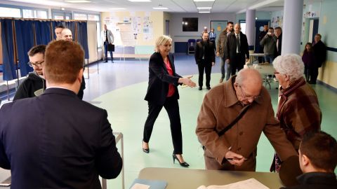 French presidential candidate Marine Le Pen moves to shakes hands with a woman at a polling station in Henin-Beaumont, France, Le Pen's home town.  
