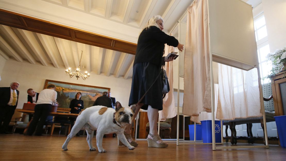 A woman with her dog enters a voting booth to cast her ballot in Saint Jean de Luz, France, on Sunday.