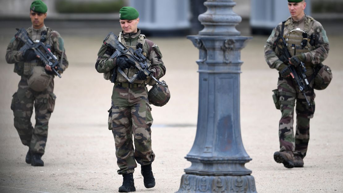 Soldiers patrol the Louvre in Paris, where Emmanuel Macron will hold a rally after polls close Sunday.