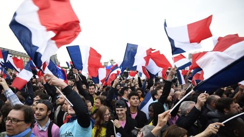 Supporters of French presidential election candidate for the En Marche ! movement Emmanuel Macron wave French national flags as they celebrate in front of the Pyramid at the Louvre Museum.