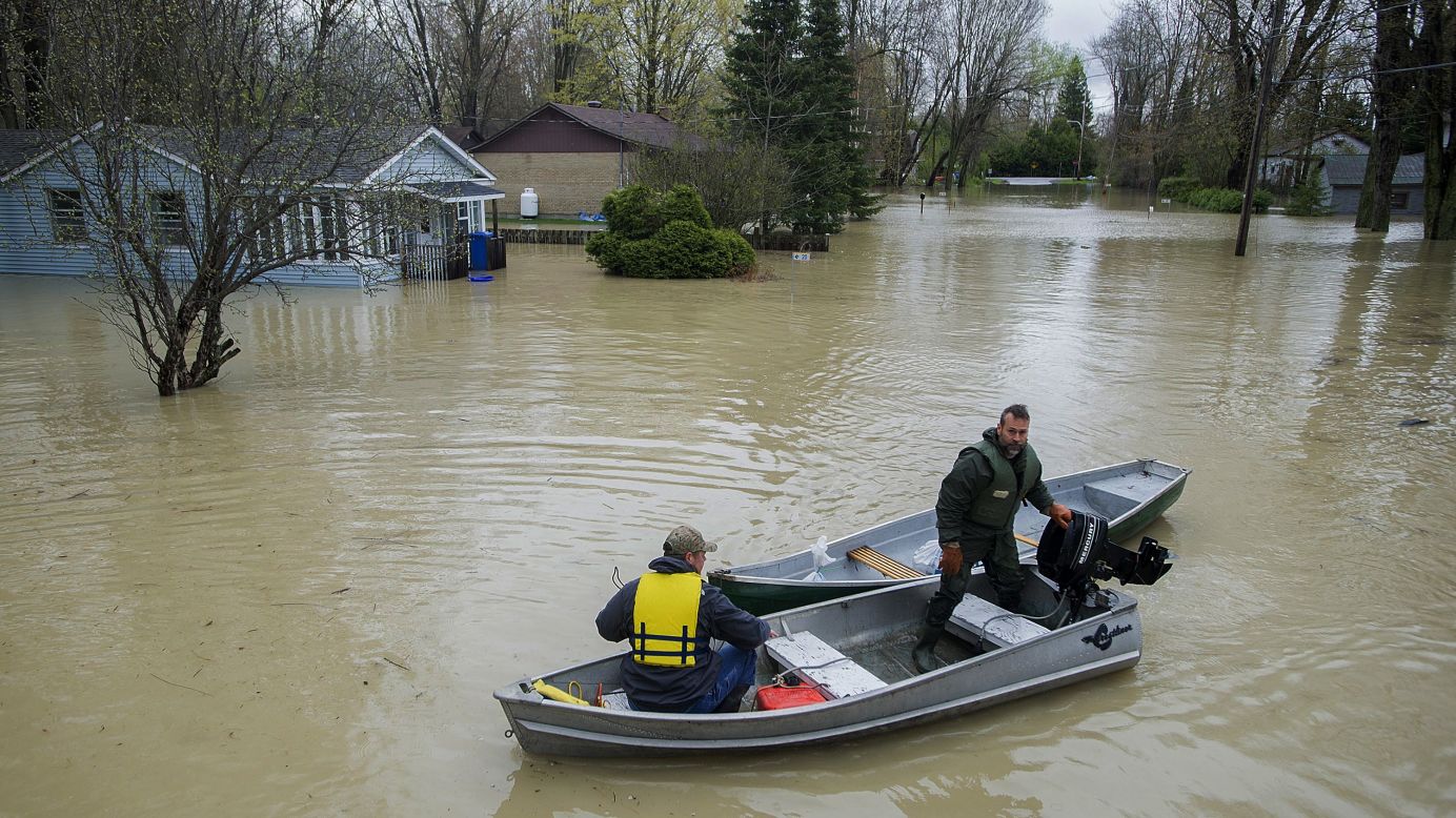 Two men navigate a flooded street in Rigaud on May 7.
