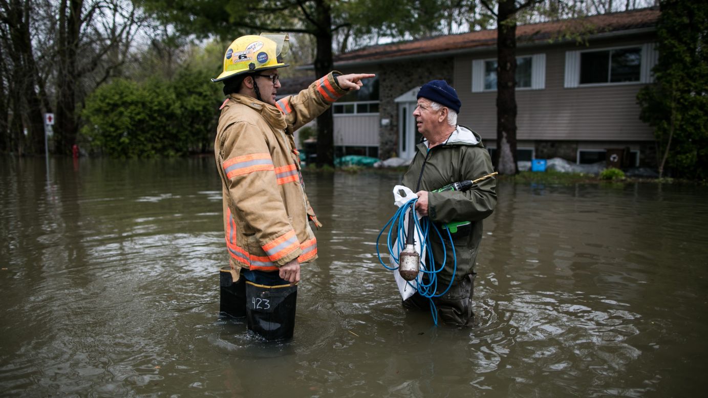 A firefighter speaks to a resident of Quebec's Mercier Island on Saturday, May 6.