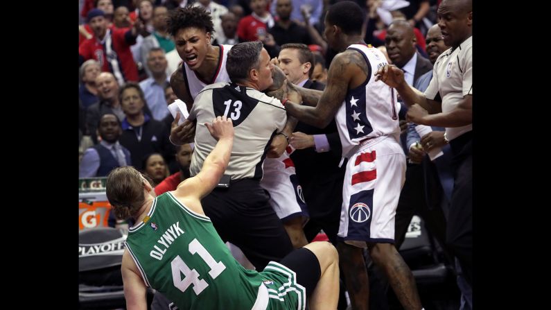 An official holds back Washington's Kelly Oubre after Oubre used his forearm to knock down Boston center Kelly Olynyk on Thursday, May 4. Oubre was ejected from the playoff game and suspended for the next one. 